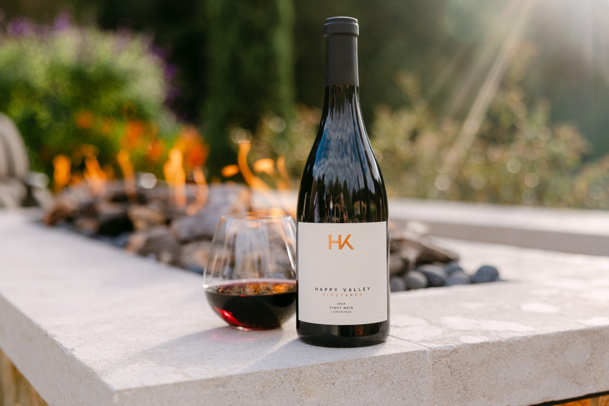 Happy Valley Vineyards Pinot Noir beside a glass of wine outdoors